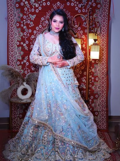 The full view of the powder blue lehenga against a traditional backdrop. The intricate details and heavy embroidery make it a standout piece.