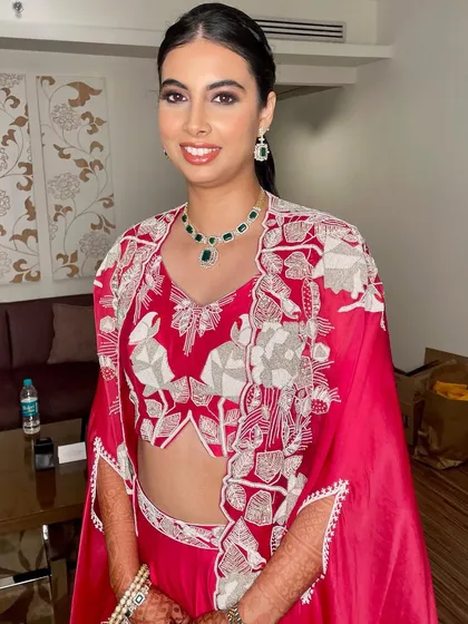 A vibrant and modern reception look. The makeup is kept clean and fresh with a defined eye to balance the bold, red embroidered outfit.