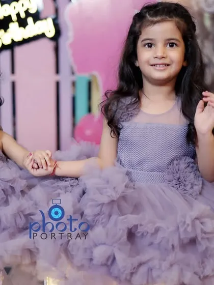 Two sisters in matching dresses hold hands during a birthday celebration. Capturing sibling relationships is a wonderful part of family photography.