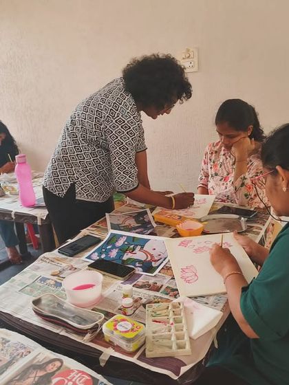 Our workshops are a community affair. Here, I'm helping a group of adult learners with their Pichwai compositions, ensuring they understand the flow and balance of the artwork.
