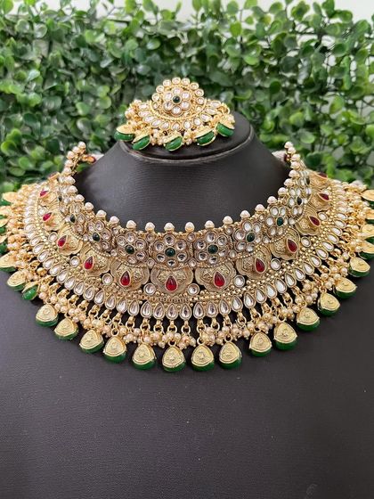 A beautiful kundan choker with delicate leaf-shaped drops, accented with red and green stones.