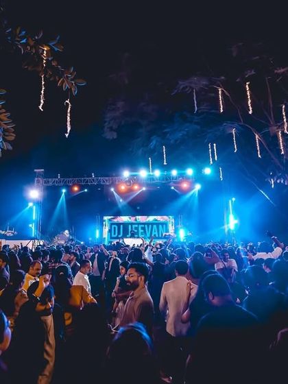The stage setup and crowd at The Lalit Bangalore, with my name lighting up the background. I am experienced in working with large event production teams to ensure perfect sound and visuals.
