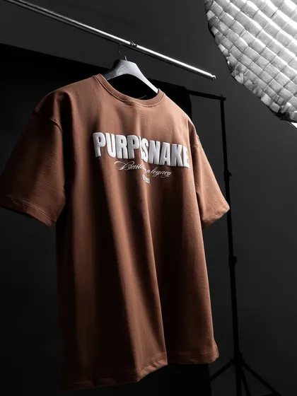 A studio shot of a t-shirt on a hanger, with lighting equipment visible. This "ghost mannequin" style shot, with a hint of behind-the-scenes, gives the product a professional and clean look for catalogues.