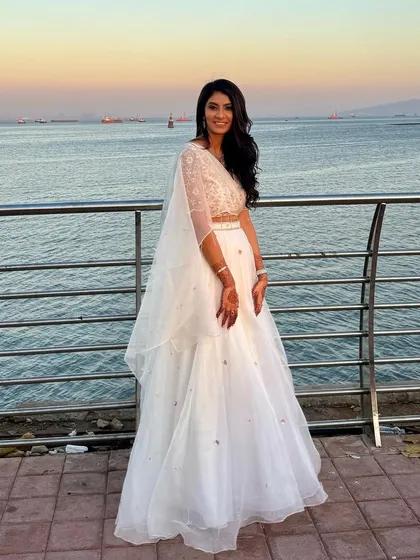 An ethereal look by the sea. This client's white lehenga was paired with a soft, glowing makeup look and long, flowing waves, creating a dreamy and romantic style for an evening event.