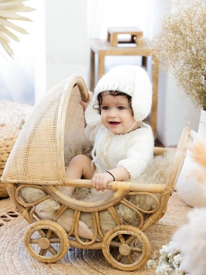 A happy baby enjoying a ride in a beautiful wicker pram. I use a variety of props to keep babies engaged and capture their genuine smiles.