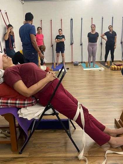 A student in a therapeutic setup for varicose veins and tired legs. The legs are elevated and supported by a bench, chair, and belts to improve circulation.