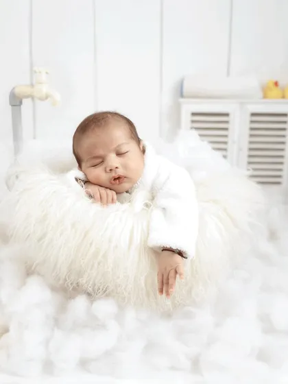 Another angle of the dreamy bath time setup, showing the baby's relaxed pose and the soft, all-white aesthetic of the scene.