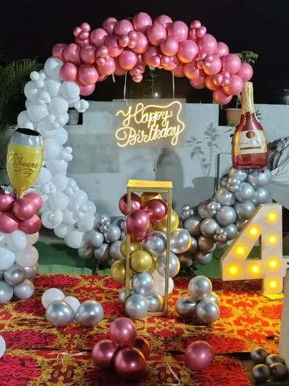 A 4th birthday terrace decoration with a balloon ring, champagne foil balloons, and a light-up marquee number.