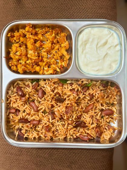 This vegetarian plate features a flavorful rajma rice, sautéed cauliflower, and a side of creamy curd.