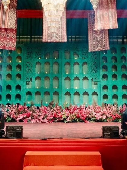 A close-up of the Moroccan-themed stage, featuring a teal laser-cut jaali backdrop and a base of vibrant pink flowers.