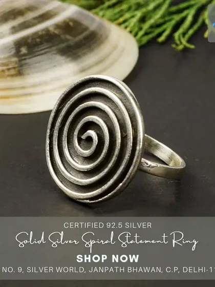 This solid silver spiral statement ring has an oxidized finish, giving it a rustic and bold look. It's a substantial piece with a powerful, modern design.