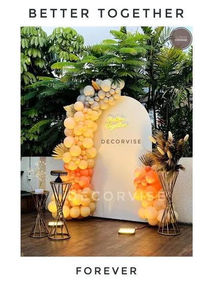 I created this chic outdoor setup for an engagement party. The 'Better Together' neon sign on a modern white arch, paired with a sunset-hued balloon garland, makes for a perfect photo opportunity for the couple.