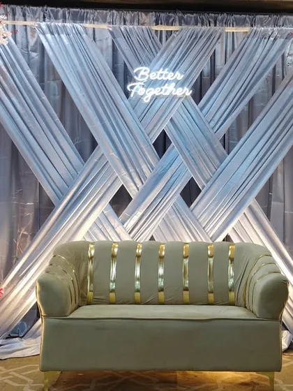 A modern engagement backdrop with crisscross silver drapes and arches of red and white flowers. The "Better Together" neon sign adds a trendy, personal touch to the stage.
