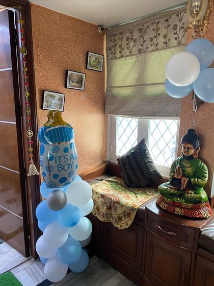 A baby bottle foil balloon on a pillar of blue and white balloons, placed in a cozy corner of the house.
