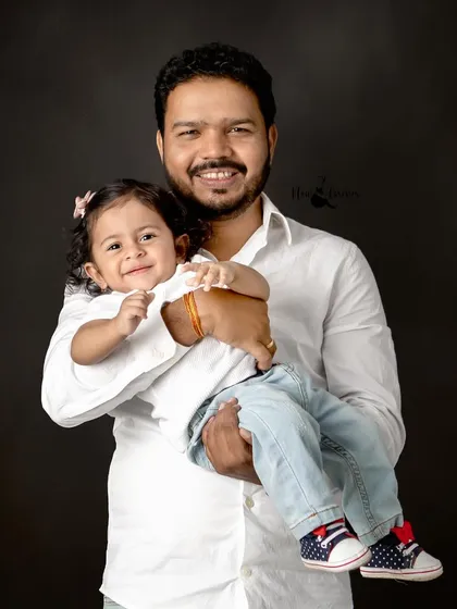 A father holds his child close, both sharing a sweet smile for the camera. This simple, classic portrait captures the strong and gentle bond between them.