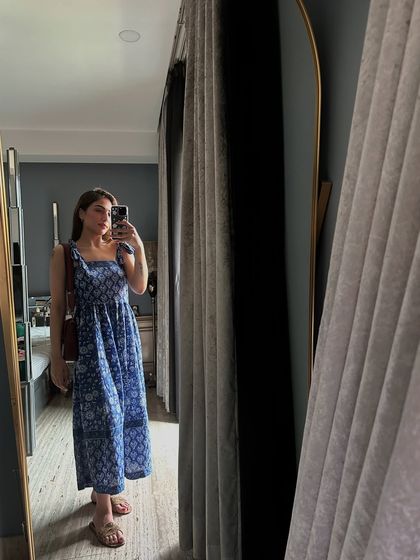 A mirror selfie in a blue block-printed summer dress. The tie-up straps and tiered design make it a comfortable and pretty choice for a hot day.