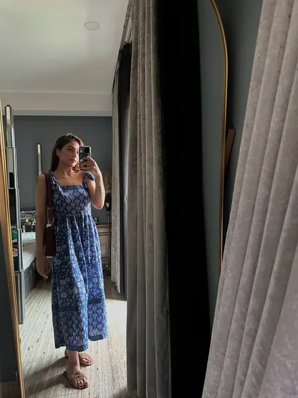 A mirror selfie in a blue block-printed summer dress. The tie-up straps and tiered design make it a comfortable and pretty choice for a hot day.