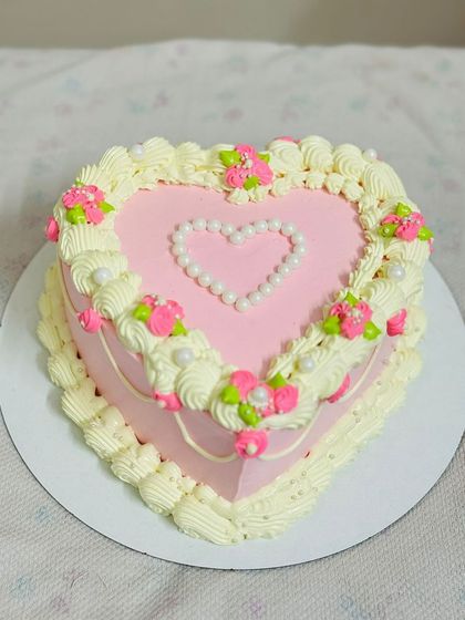 A vintage-style heart-shaped cake with intricate piping and pearl details.