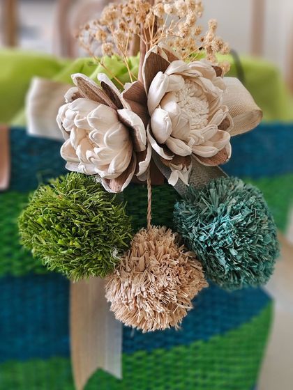 A close-up of the beautiful, handcrafted tassel on one of my eco-friendly baskets. I use dried flowers and colorful raffia pom-poms to create these unique embellishments.