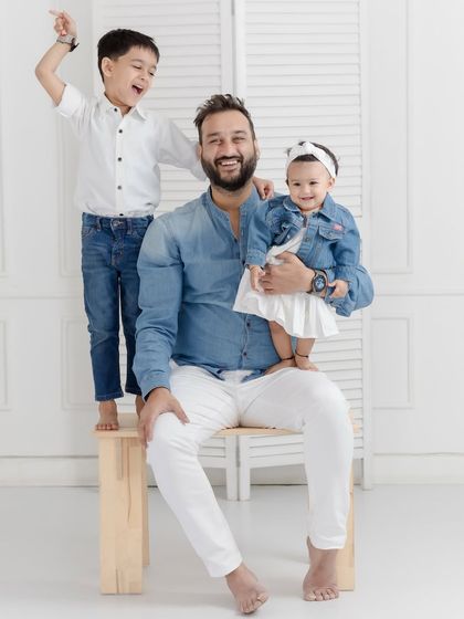 A fun and playful portrait of a father with his two children. The older brother's joyful expression and the baby's sweet smile make this a treasured memory.