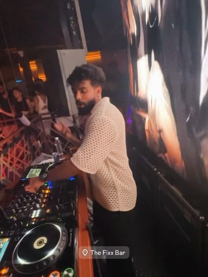 A candid shot of me at the decks at The Fixx Bar, with the visuals on the screen behind me.
