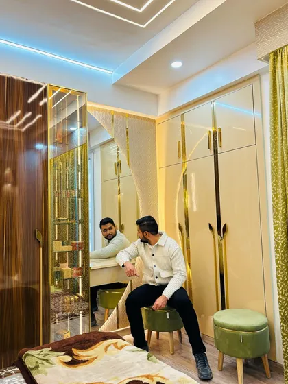 This bedroom design at Prateek Laurel showcases luxury and smart storage. I designed a floor-to-ceiling wardrobe with a mix of wood grain and high-gloss beige laminate, accented with gold profiles, and integrated a full-sized dressing unit with its own dedicated lighting.
