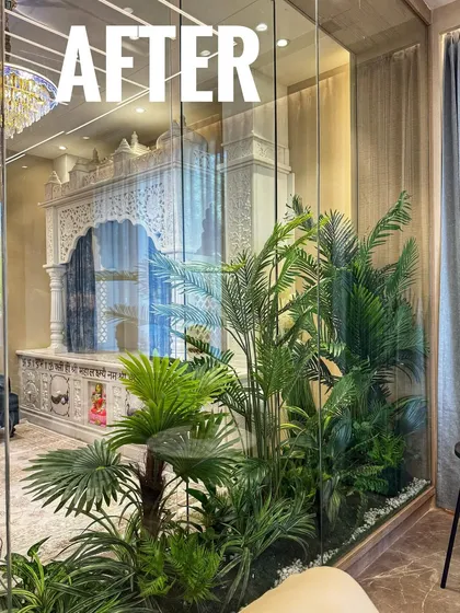This is how we transform challenging indoor spaces. For this home's pooja room, enclosed in glass with no direct sunlight, we created a tropical paradise using high-quality artificial palms and foliage for a vibrant, everlasting look.