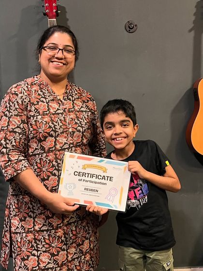 An instructor proudly presents a certificate of participation to a young student, Reuben, recognizing his dedication and hard work.
