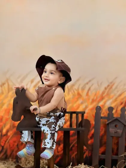 Giddy up. A little cowboy enjoys a ride on a rocking horse in a rustic farm setting with a scarecrow in the background.