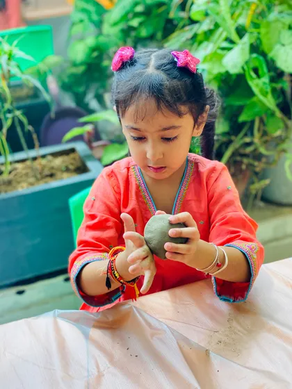 A young artist carefully shaping her Ganesha idol. Working with clay is a wonderful sensory experience that helps build hand strength and coordination.