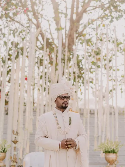 The groom, Rahul, waits for his bride, looking sharp in his sunglasses and elegant attire.