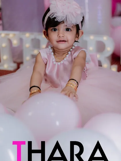 A first birthday is a whirlwind of color and fun. We capture the heart of the celebration, focusing on the birthday girl amidst the festive decor, like Thara here surrounded by a sea of pink and white balloons.