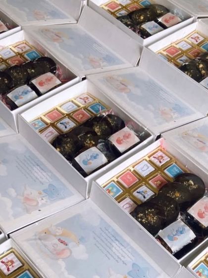 A look at a bulk order of baby announcement hampers for twins. These boxes are filled with custom-printed chocolates and other treats to share the joyous news.