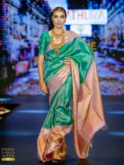 The model strikes a pose, showing off the shimmering quality of the sea-green silk and the wide, elegant peach border.