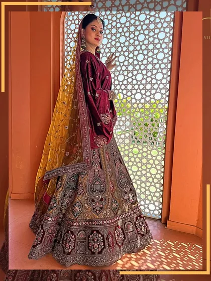 The rich colors and detailed embroidery of this bridal lehenga are captured perfectly in this shot by the window.