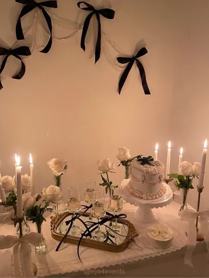 We love playing with bold themes, like this chic black and white dessert table. The setup features elegant white roses, classic tapered candles, and delicate black ribbon details for a modern and sophisticated aesthetic.