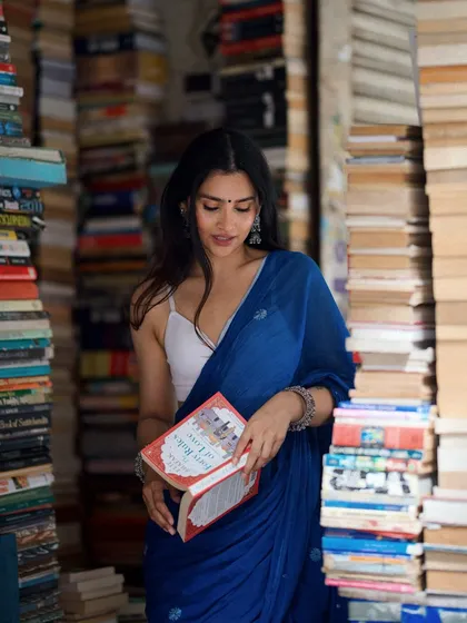 Another angle from the saree shoot, showing the texture of the fabric and the endless stacks of books.