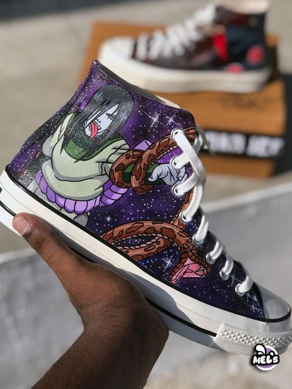 A hand-held shot of the Orochimaru custom Converse. The design features the serpentine villain against a sparkling purple galaxy background, with his snake companion wrapped around him.