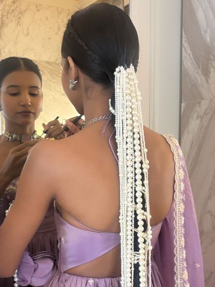 A behind-the-scenes look at styling influencer Nancy Tyagi. This long, sleek braid is dramatically adorned with cascading strings of pearls, creating a high-fashion, ethereal look.