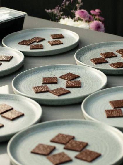 Plates of craft chocolate squares ready for tasting. In our workshops, we guide you through a curated selection, explaining the origin of the beans and the process that gives each bar its unique flavor profile.