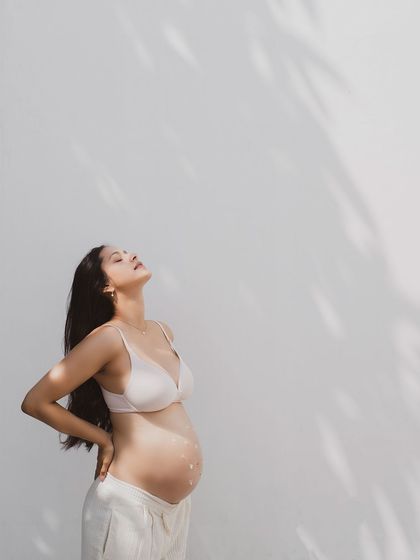 A stunning maternity photo, with the mother-to-be basking in the sunlight. The shadows create a beautiful, artistic pattern on the wall.