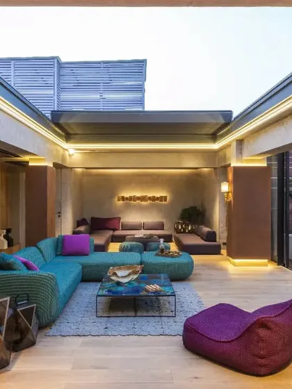This vibrant lounge in a New Delhi residence is an entertainment area designed for soulful moments. We used eclectic Paola Lenti furniture against concrete and rust-finished walls, with a retractable roof for a seamless connection to the outdoors.