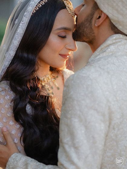 A close-up of a tender forehead kiss, a classic symbol of love and protection. This intimate moment, captured in beautiful soft light, is a timeless memory from their wedding day.