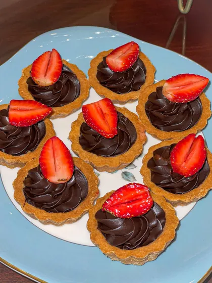 Mini chocolate tarts topped with fresh strawberries. These bite-sized treats are perfect for a dessert table or high tea.