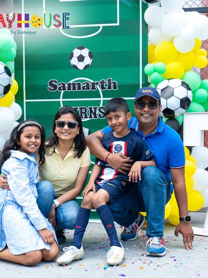 A perfect family portrait at Samarth's 7th football-themed birthday party, set against a backdrop of a soccer field and balloons.