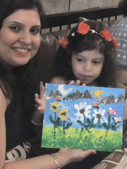A mother and daughter duo showing their beautiful floral painting, a shared creation from Vazeeshtha's art-themed birthday party.