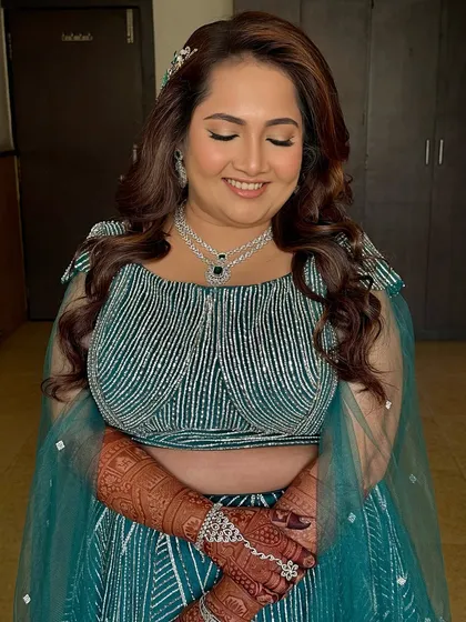 A beautiful smiling shot with eyes closed, showing the soft blending on the eyelids and the radiant finish of the skin. A perfect sangeet glow.