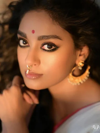 An extreme close-up focusing on the model's expressive eyes, bindi, and pearl nose ring. This shot highlights the subtle yet powerful details of the traditional look.