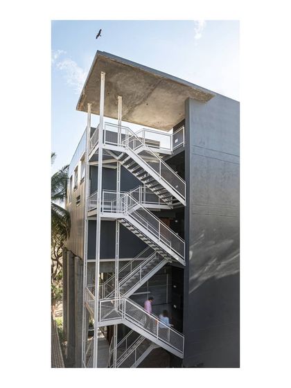 The external staircase is a transparent, suspended structure held by a 6-meter cantilevered raw concrete roof. This design choice keeps the circulation visible and light, expressing the structural forces at play.