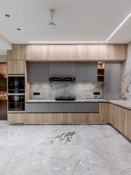 This kitchen, designed with The Grid Architects, combines matt grey lacquer with a warm wooden laminate. The Brazilian granite backsplash and countertop add a dramatic, artistic element.